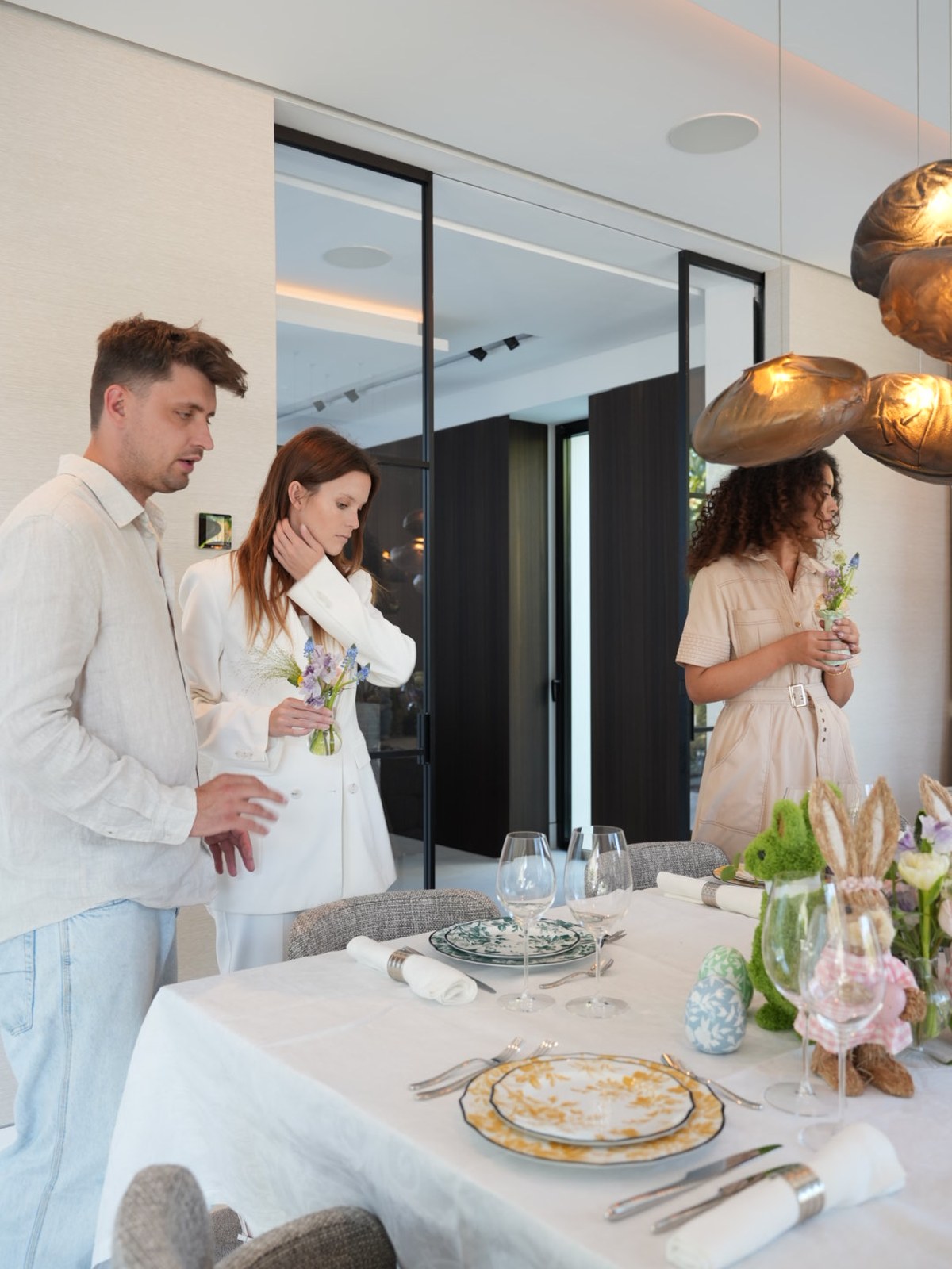 A team dressed in white and cream arranging flowers and place settings at an Easter table