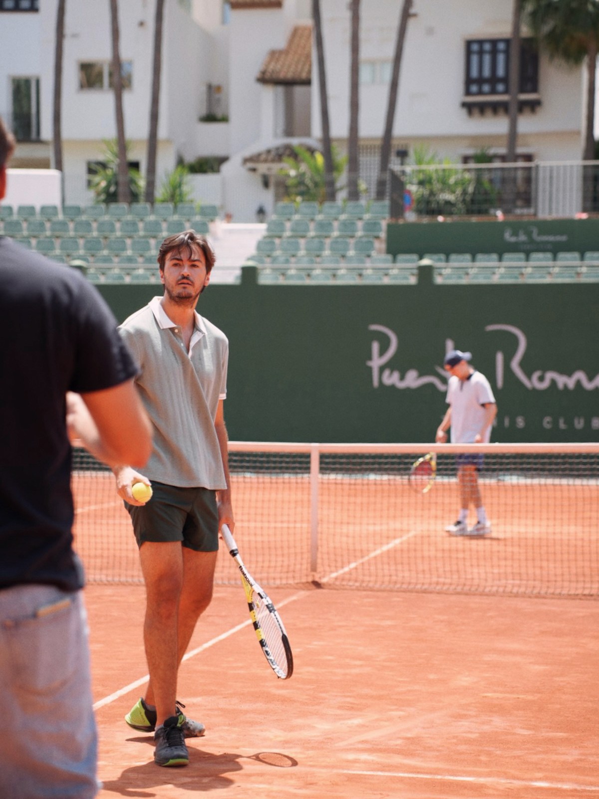 A man with a tennis racket on the clay court at Puente Romano tennis club in Marbella