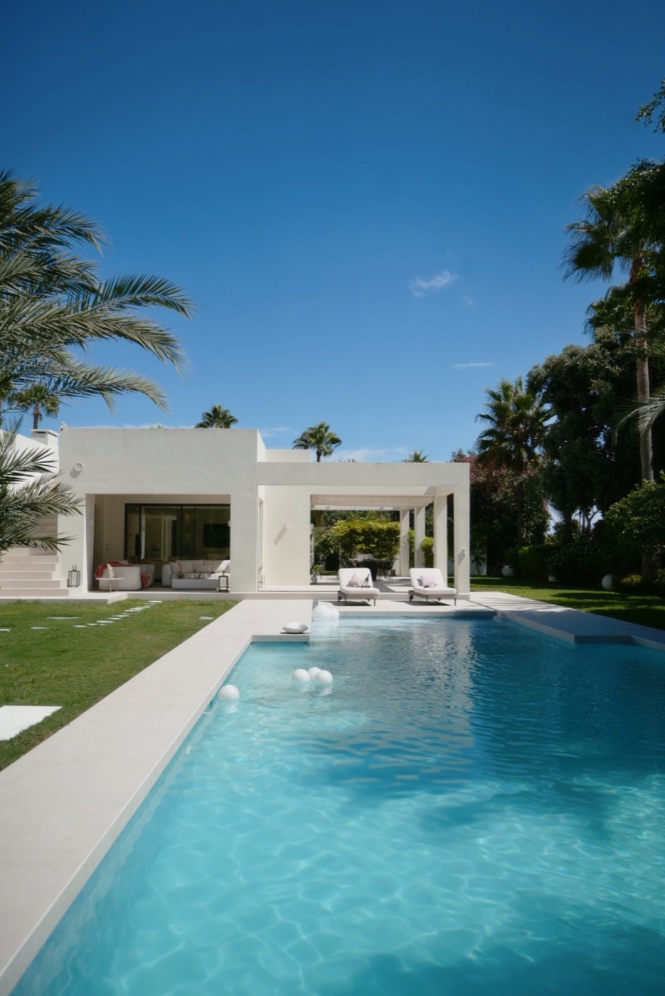 Modern white villa with a long pool framed by palm trees