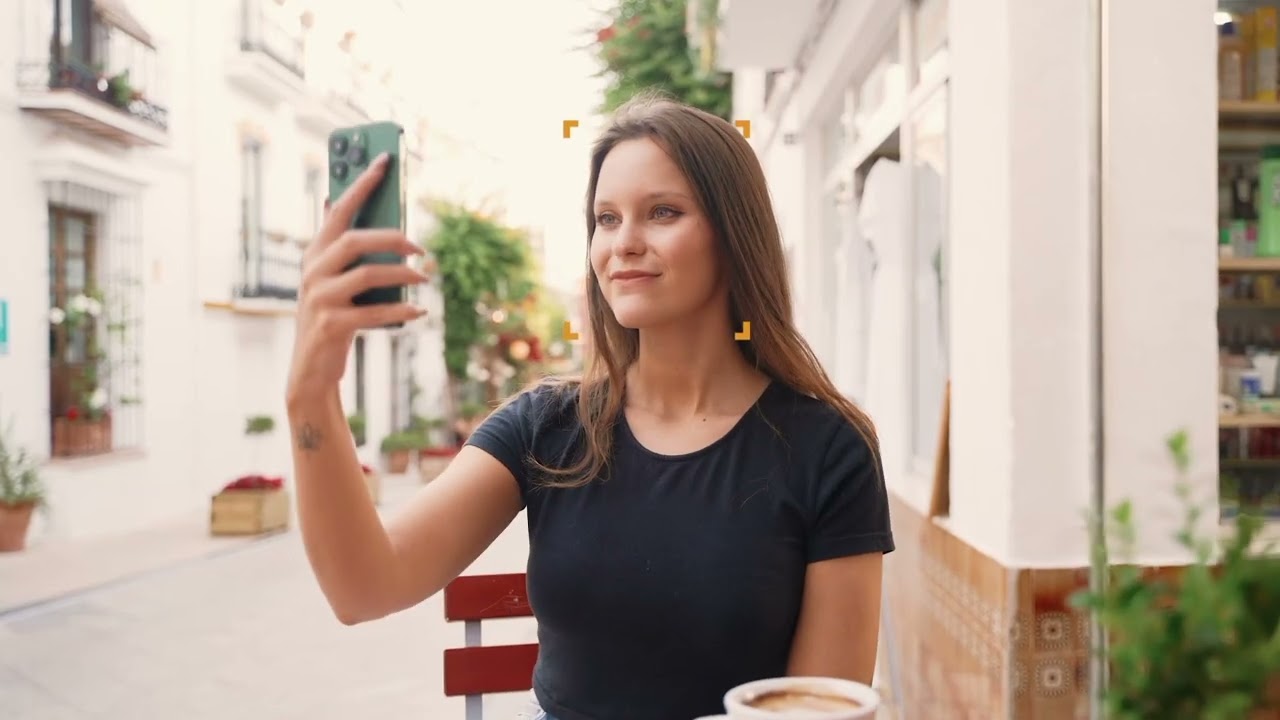 Filming lifestyle content on a phone at an outdoor cafe in a Marbella street