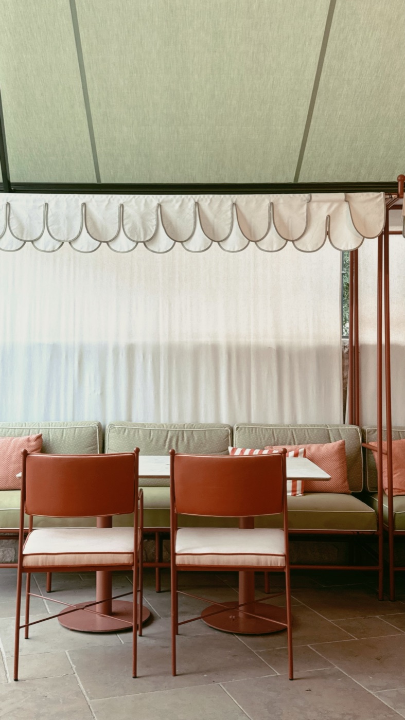 Stylish restaurant terrace with terracotta chairs, green banquette and a scalloped awning