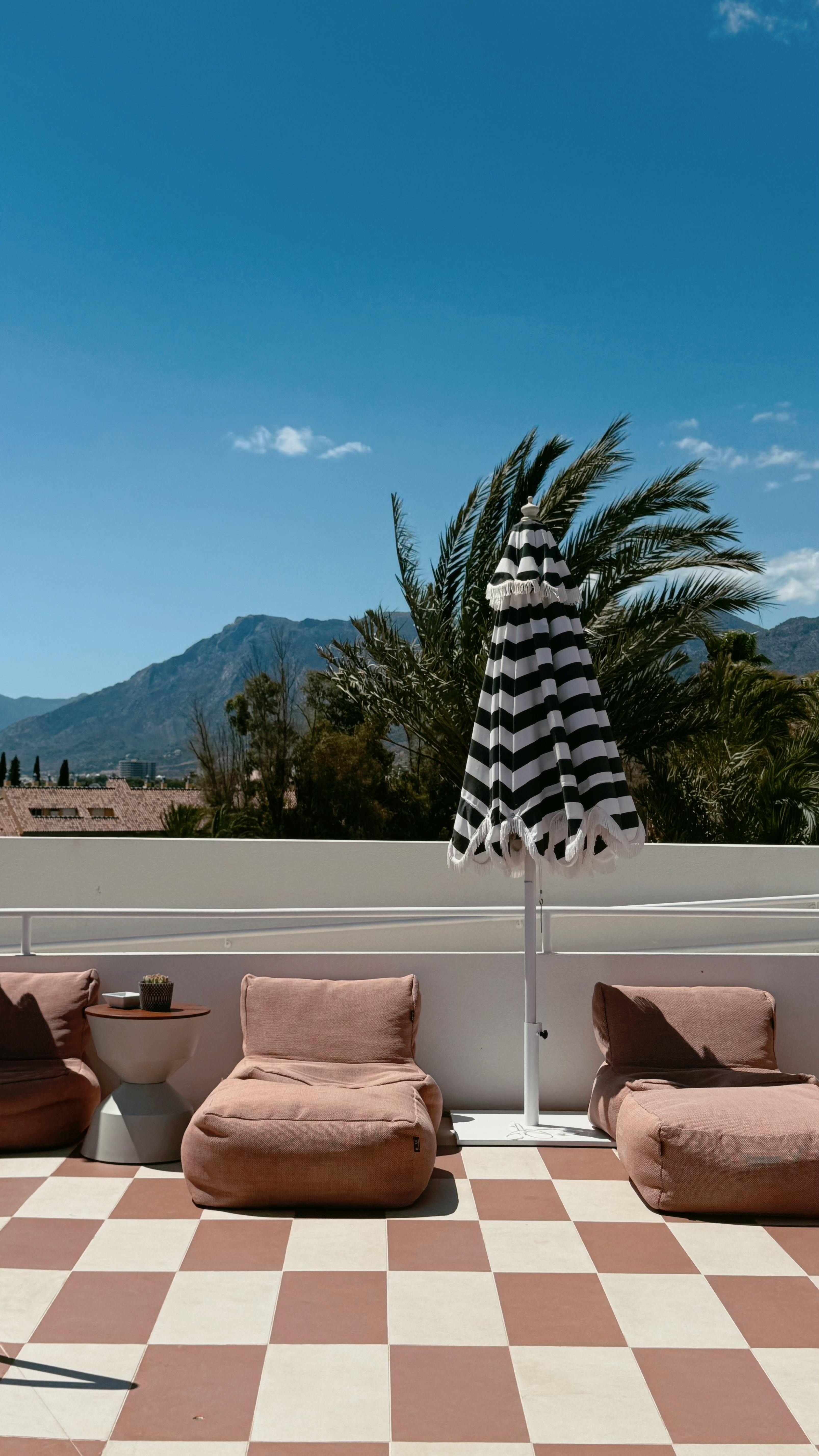 Rooftop lounge with terracotta bean bags and a striped parasol over the mountains