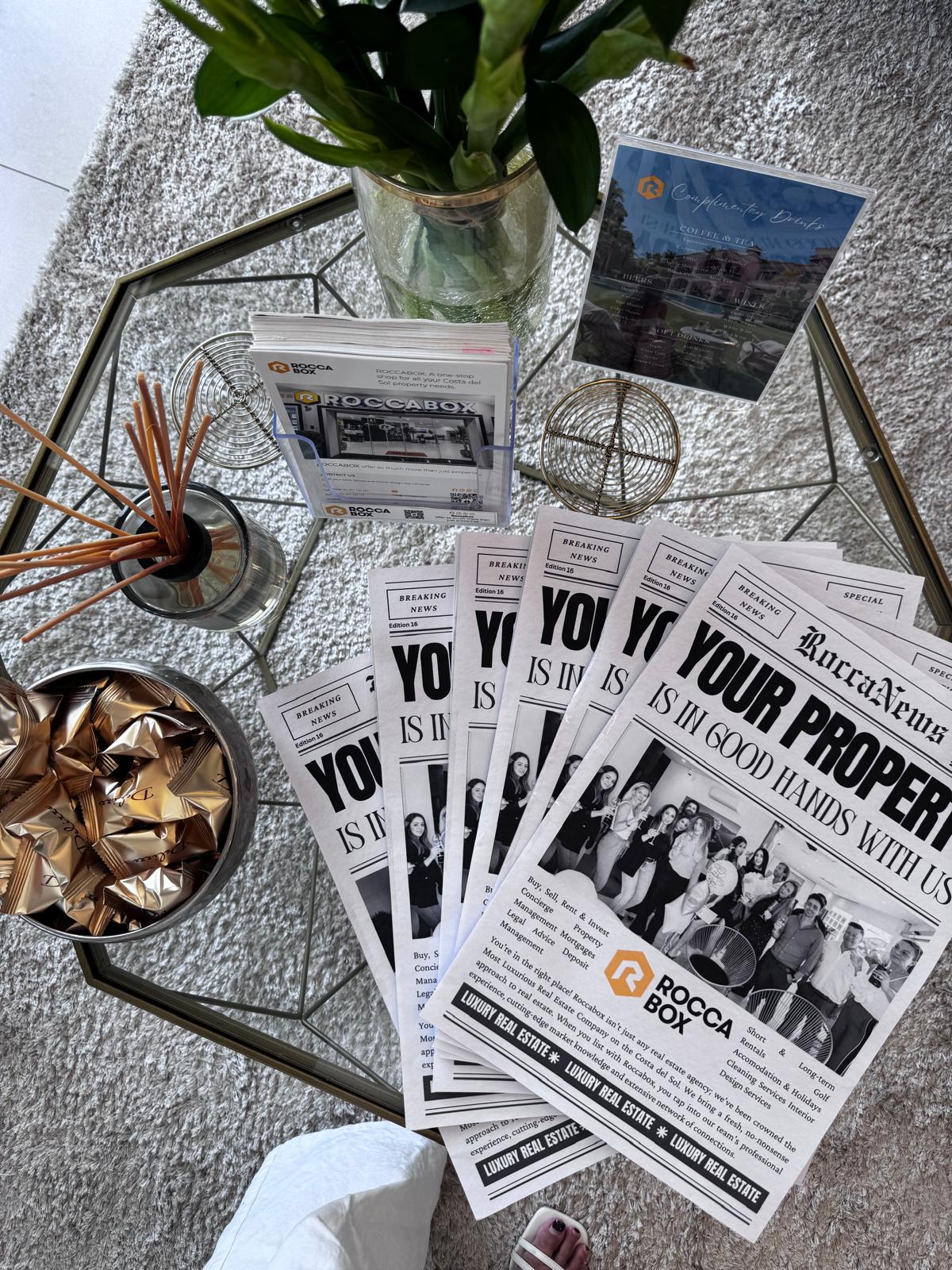 RoccaNews newspapers and branded collateral styled on a coffee table